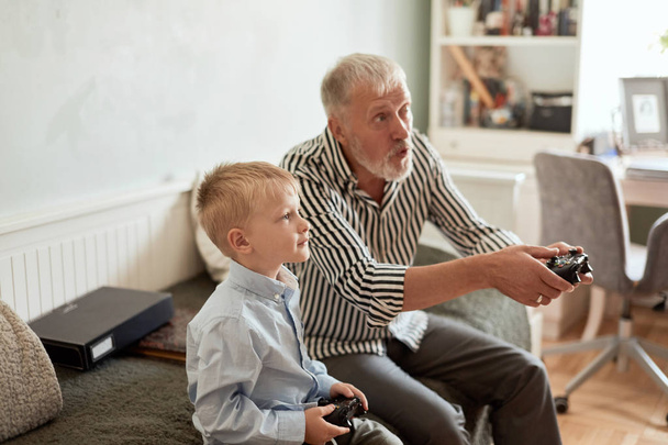 Grandfather and grandson playing video games on computer with joystick - Фото, изображение