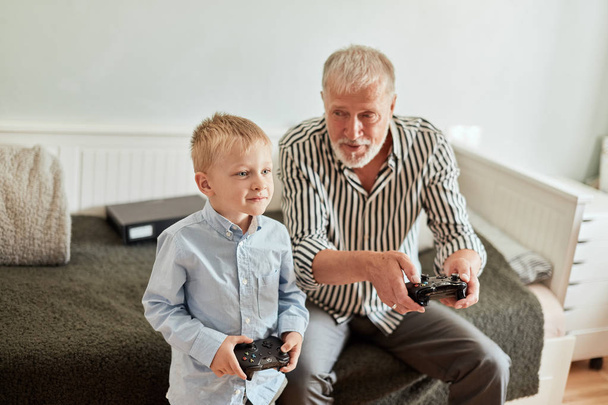 Grandfather and grandson playing video games on computer with joystick - Фото, зображення