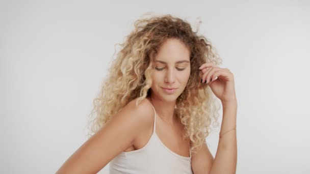 Model im Studio mit großen lockigen blonden Haaren auf weißem Hintergrund mit natürlichem Make-up - Filmmaterial, Video