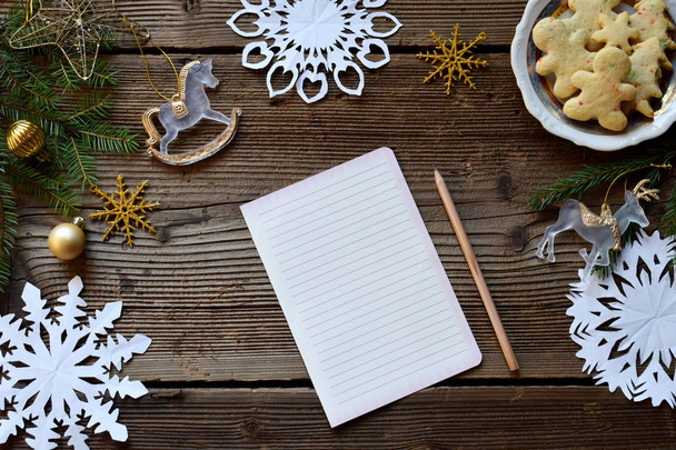 サンタ クロースの手紙。しい物のリスト。クリスマスの装飾、雪片紙、木製の背景にジンジャーブレッド人。冬の休日のコンセプトです。コピー スペース平面図. - 写真・画像