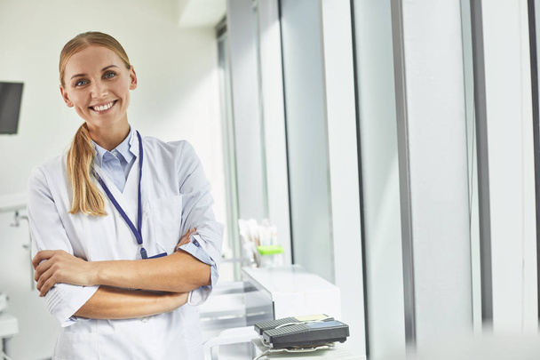 Smiling female doctor standing in medical office - 写真・画像