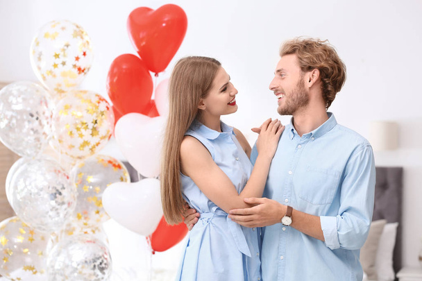 Young couple with air balloons at home. Celebration of Saint Valentine's Day - Фото, изображение