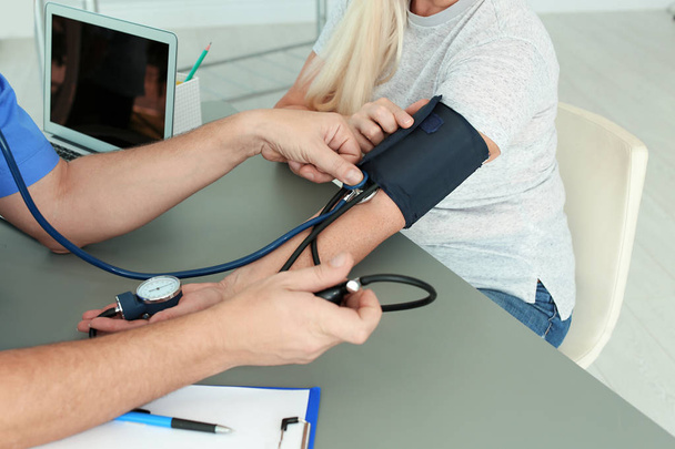 Close up view of medical assistant measuring female patient blood pressure in clinic - 写真・画像