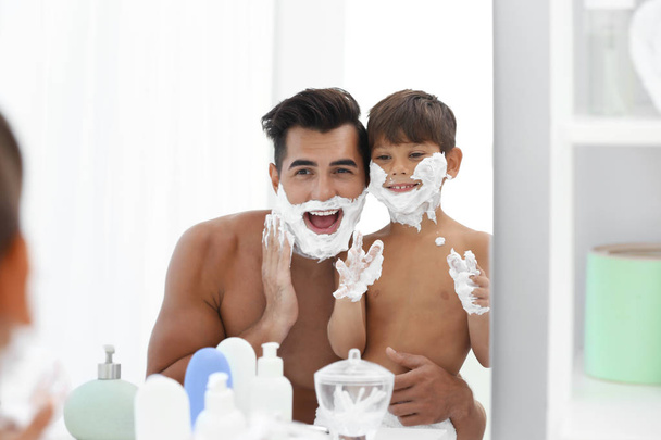 Father and son having fun while applying shaving foam in bathroom - Foto, Imagen