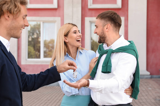 masculino agente imobiliário dando casa chave para casal ao ar livre
 - Foto, Imagem
