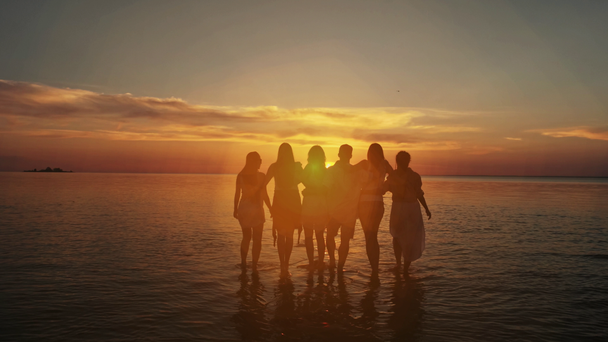 Csoport öt boldog ember ül a háttérben üres sunset Beach. Utazási vagy tengeri vakáció koncepció - Felvétel, videó