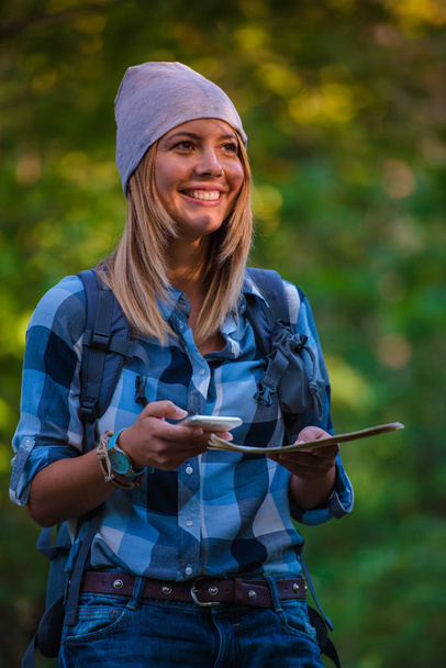 Giovane donna che cammina da sola nel bosco con in mano una mappa. Concetto escursionistico in montagna in estate
 - Foto, immagini