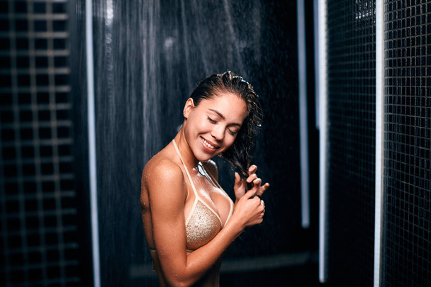 Beautiful caucasian brunette woman taking shower in her black luxury bathroom. - Фото, зображення