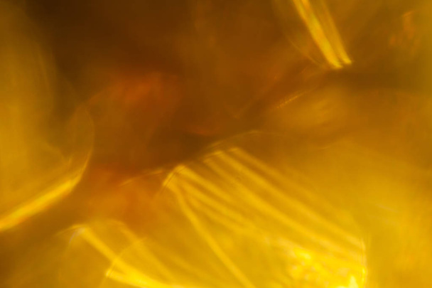 Крупный план гладких пятен яркого золотистого света, сверкающих в темной комнате
 - Фото, изображение