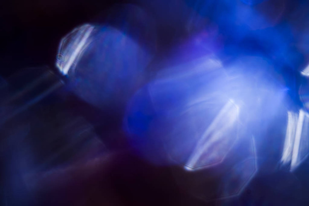 Close-up shot van ronde vlekjes van prachtige blauw en violet licht lichtpuntje op zwarte achtergrond - Foto, afbeelding