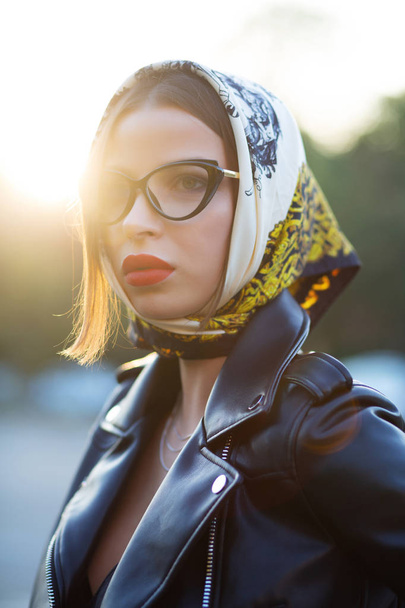 Street shot of fashionable brunette woman with red lips wearing shawl and glasses - Fotó, kép