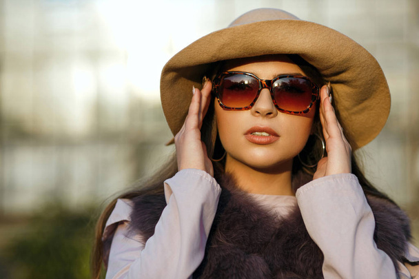 Модная брюнетка загорелая женщина с натуральным макияжем в шляпе, солнцезащитных очках и шубе. Пространство для текста
 - Фото, изображение