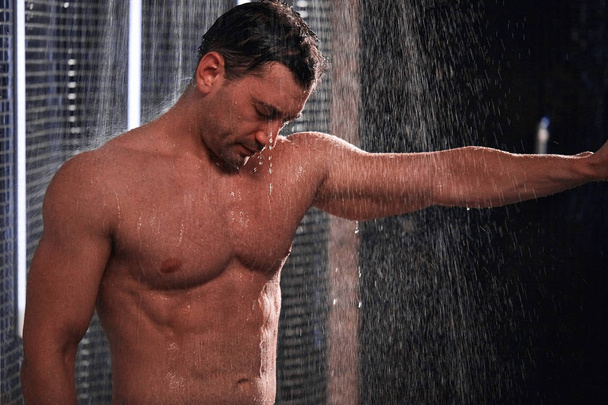 Handsome man taking shower, refreshing himself after a hot working day. - Photo, image
