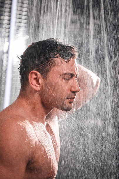 Handsome man taking shower, refreshing himself after a hot working day. - Foto, Imagem