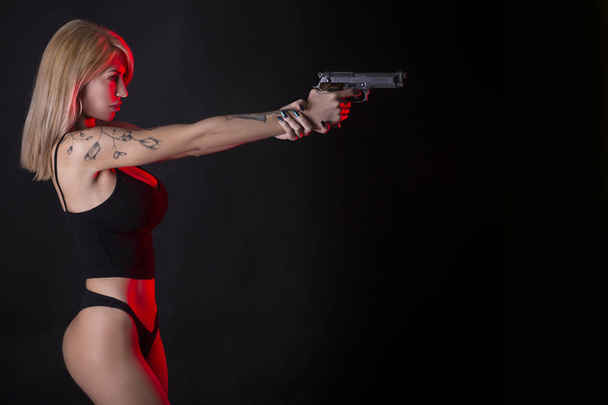 Sexy vrouw in zwarte pak met assault rifle. - Foto, afbeelding