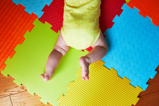 Baby girl doing tummy time on colorful play mat. Happy healthy kid playing on the floor - Foto, Imagem