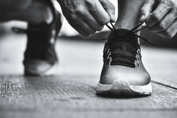 Hands of sportsman with pedometer tying shoelaces on sporty sneaker. Running equipment concept. Shoelaces tying by male hands. - Photo, Image