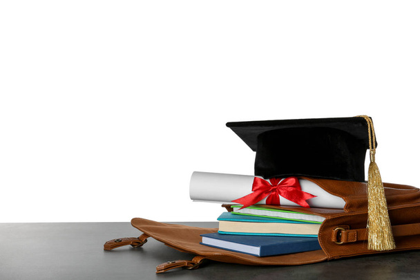 Briefcase with books, diploma and graduation hat on table against white background - Foto, immagini