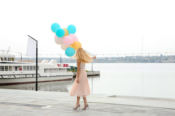 Mooie jonge vrouw met een heleboel ballonnen buitenshuis - Foto, afbeelding