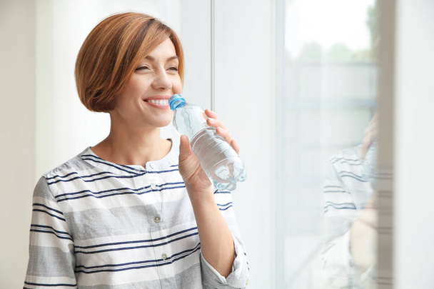 Woman holding glass with clean water in kitchen - Foto, Bild