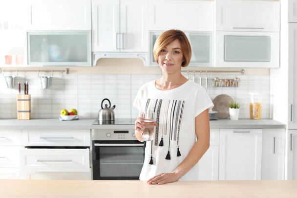 Woman holding glass with clean water in kitchen - Photo, Image