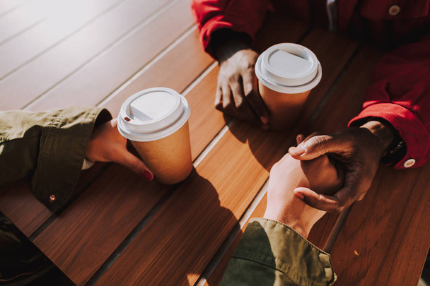 Close up of two people holding hands and drinking coffee - Fotografie, Obrázek
