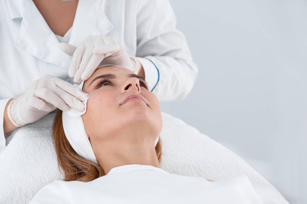 Woman undergoing face biorevitalization procedure in salon. Cosmetic treatment - 写真・画像