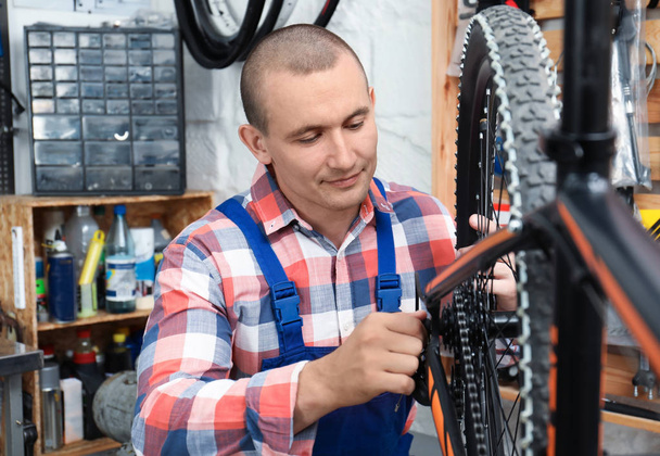 Professional mechanic repairing bicycle in modern workshop - Фото, изображение