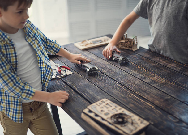 zwei Jungen halten Spielzeugautos und machen Rennen auf dem Tisch - Foto, Bild
