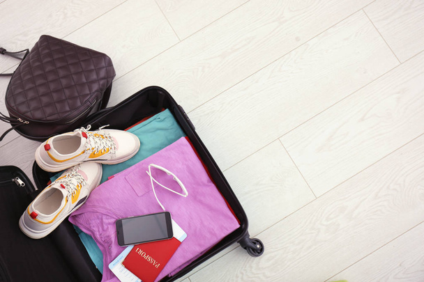 Modern suitcase full of clothes on wooden floor, top view with space for text - Fotoğraf, Görsel