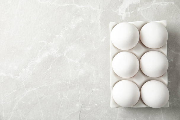 Huevos de pollo crudos en soporte de cerámica sobre fondo claro, vista superior. Espacio para texto
 - Foto, Imagen