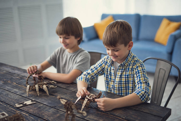 Two boys smiling while making mechanic models from wooden constructor - Fotoğraf, Görsel