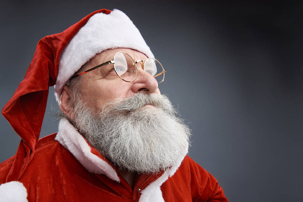 Serene Santa Claus in glasses posing on gray background - Foto, Imagem