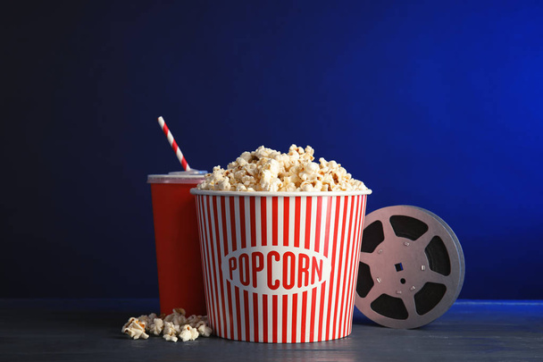 Composition with popcorn and cinema reel on table against color background - Fotó, kép