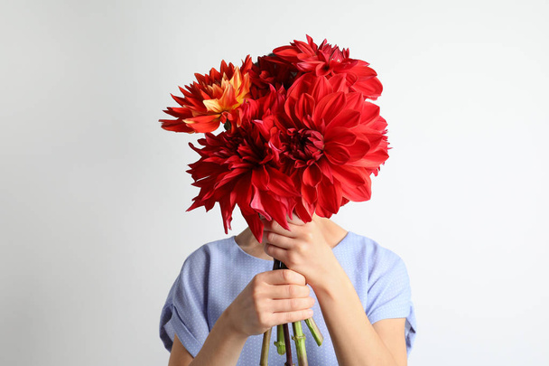 Woman holding bouquet of beautiful dahlia flowers against light background - 写真・画像