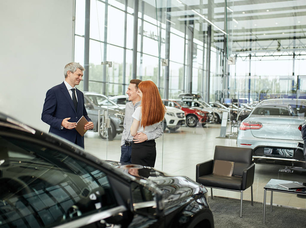 Happy beautiful couple is buying a new car at dealership. Family council - Valokuva, kuva