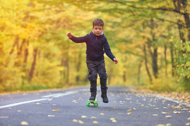 Kid skateboarder doing skateboard tricks in autumn environment - 写真・画像