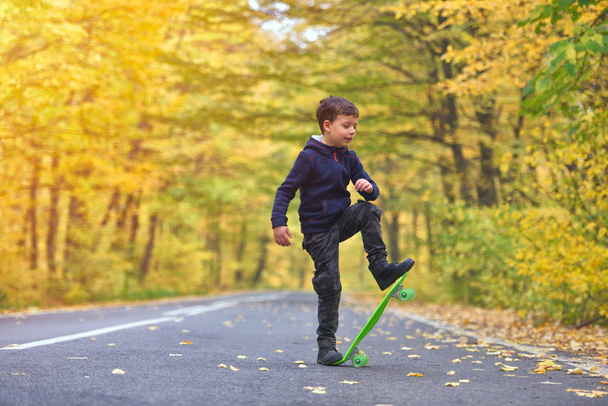 Ребенок скейтбордист делает трюки на скейтборде в осенней среде
 - Фото, изображение