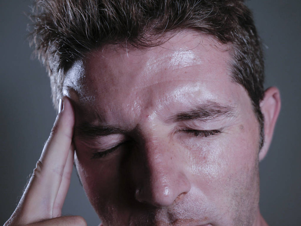 close up isolated portrait of young handsome and overwhelmed man suffering headache and migraine feeling sick and unwell touching his tempo in pain looking frustrated and stressed - Photo, image
