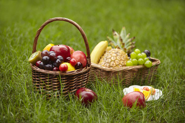 assorted fruits in baskets for picnic on grass. - Foto, Imagen