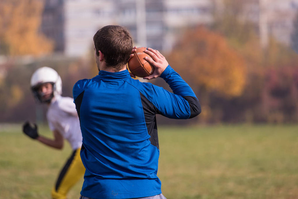 Team coach throwing the ball into the group of young american football players in action during the training at the field - Fotografie, Obrázek