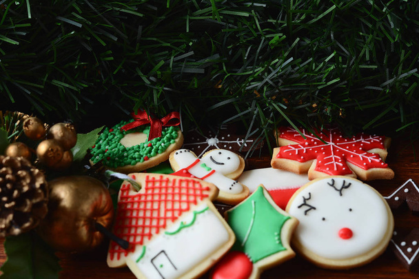 Close up view of colorful Christmas cookies with festive decoration on wooden table. xmas holiday concept. - Fotó, kép