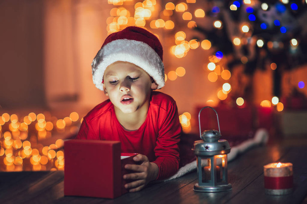 Удивлённый ребёнок открывает волшебный рождественский подарок. Рождественский праздник
 - Фото, изображение