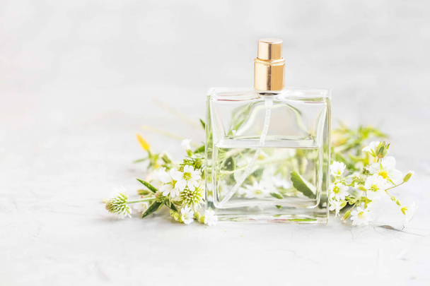 Парфумерна пляшка з білими квітами, білий квітковий аромат парфумів у прозорій пляшці
 - Фото, зображення