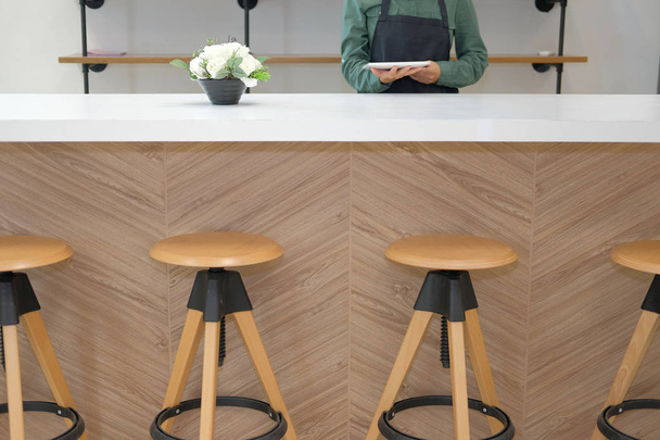 işletme sahibi tablet sayaç barda tutan önlük giyiyor. Touchpad Cafe kahve salonu kafeterya restoranda kullanan adam - Fotoğraf, Görsel