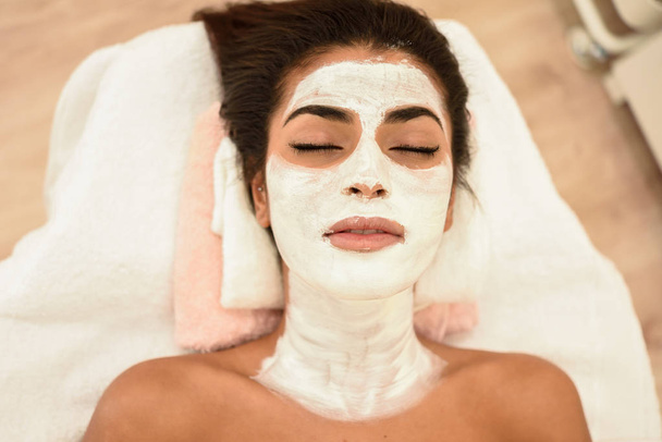 Young woman with moisturizer cream mask on her face in modern wellness center. Beauty and Aesthetic concepts. - Photo, Image