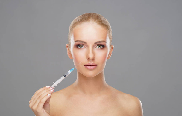 Genç bir kadının yüzüne güzellik aşısı. Estetik ameliyat, cilt gerdirme ve estetik tıp konsepti. - Fotoğraf, Görsel