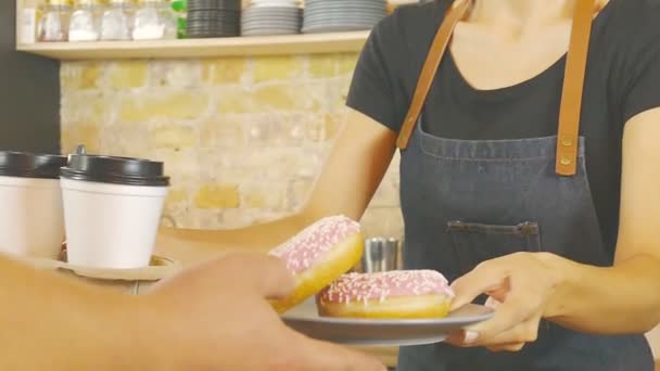 Smiling waitress giving cup of coffee and donats to the customer. - Filmati, video