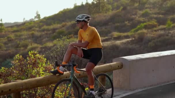 Man cyclist resting after arrival and admiring the view of the mountains - Footage, Video