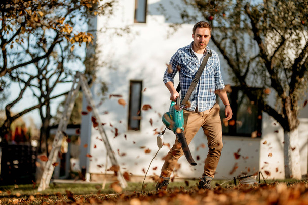 Landscaping details, worker using leaf blower and cleaning up the garden - Foto, Bild